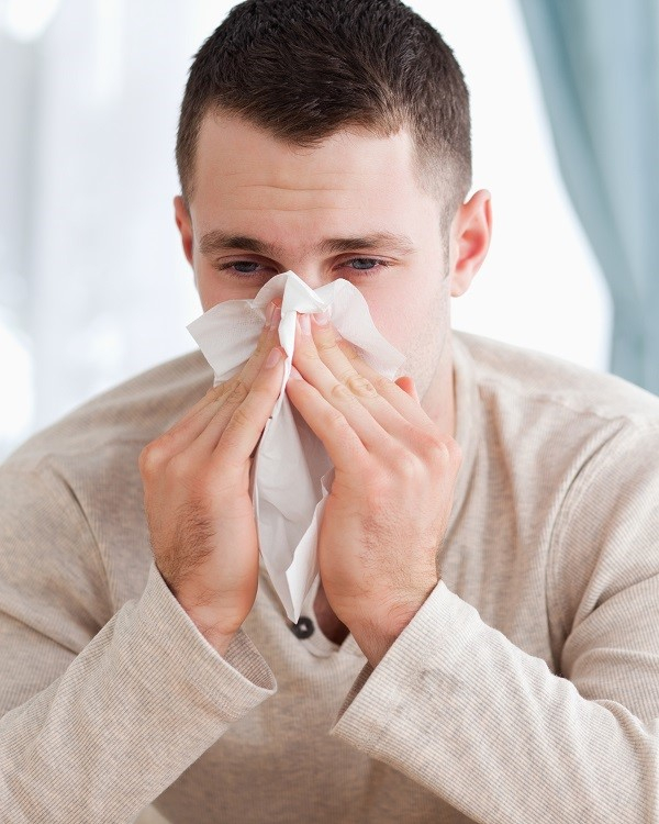 Man blowing his nose in his living room