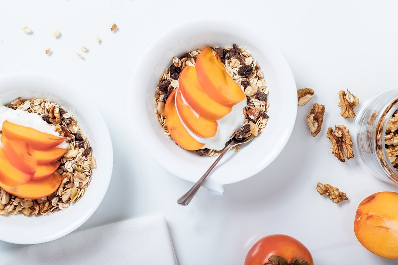 Yogurt with fruit and nuts on white background