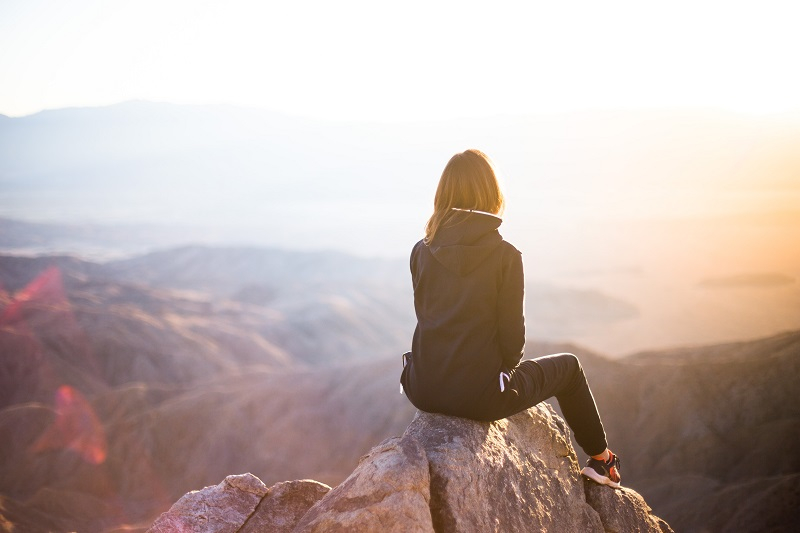 A woman sitting in the mountains with an amazing view