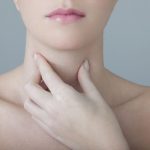 Woman touching her Thyroid