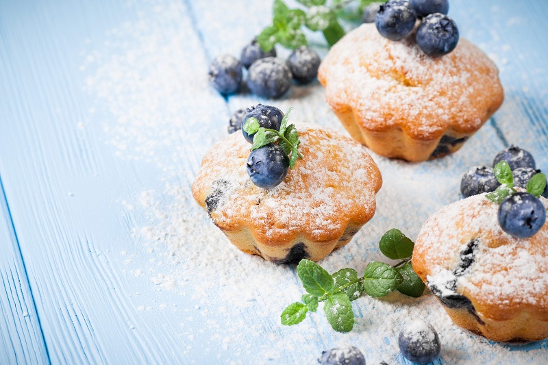 Homemade muffins with blueberries on blue background