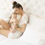 Mother with baby on white bed Post partum recovery